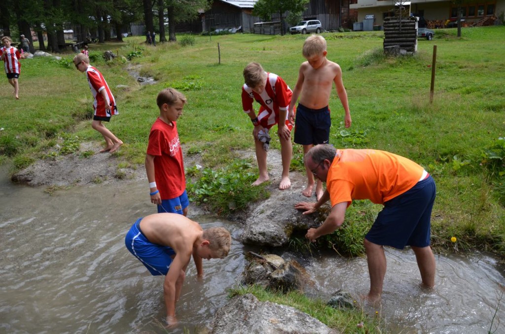 Kleine und grosse Jungs stauen gemeinsam das Bächlein (Foto: Simon Abächerli)